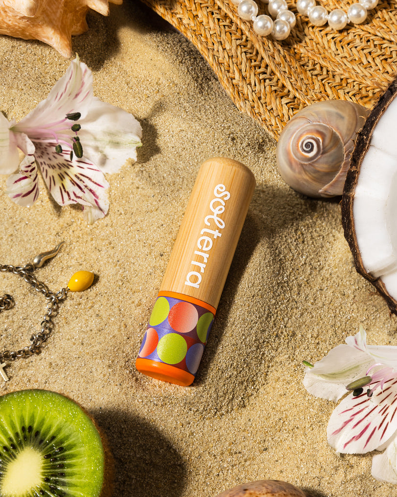 Colorful lip balm with Solterra branding on a sandy surface with flowers and shells.